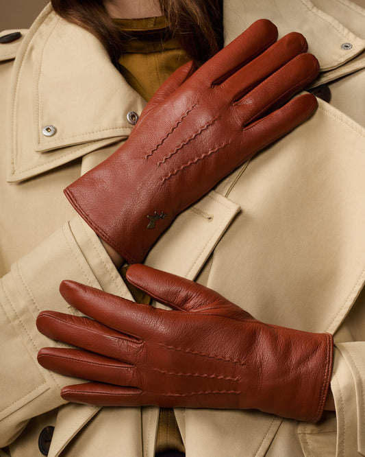 Cognac brown leather gloves laid flat with stitched seams and long cuffs