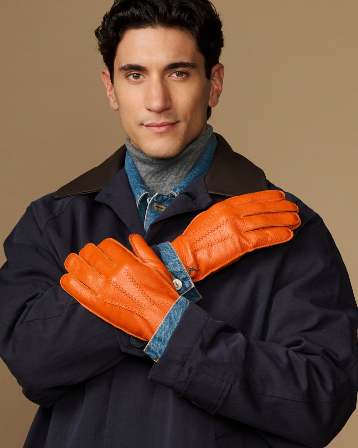 Men’s orange deerskin leather gloves with blue lining, worn under a dark coat