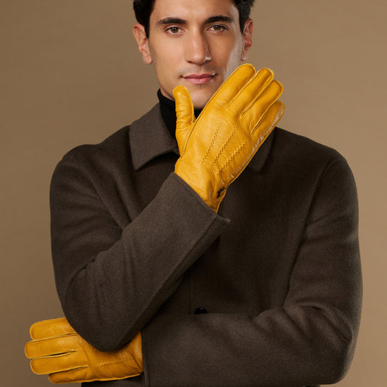 Yellow leather gloves on model with one glove raised near face