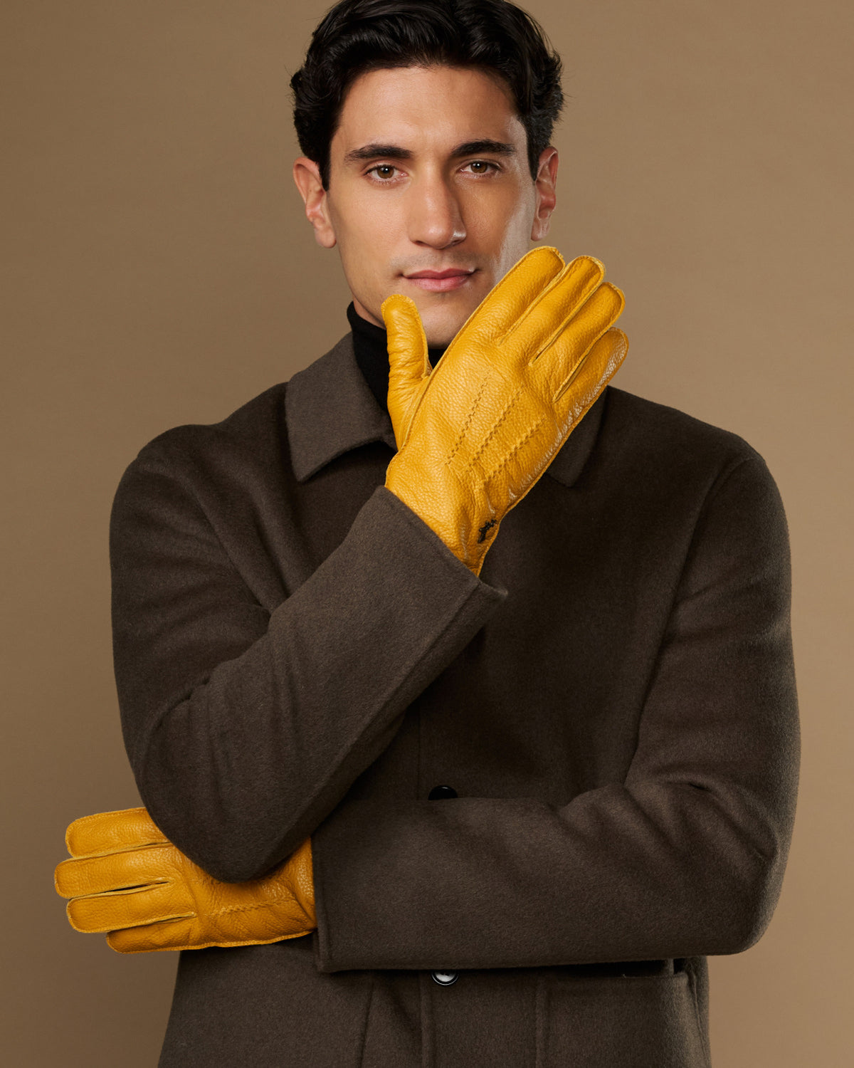 Yellow leather gloves on model with one glove raised near face