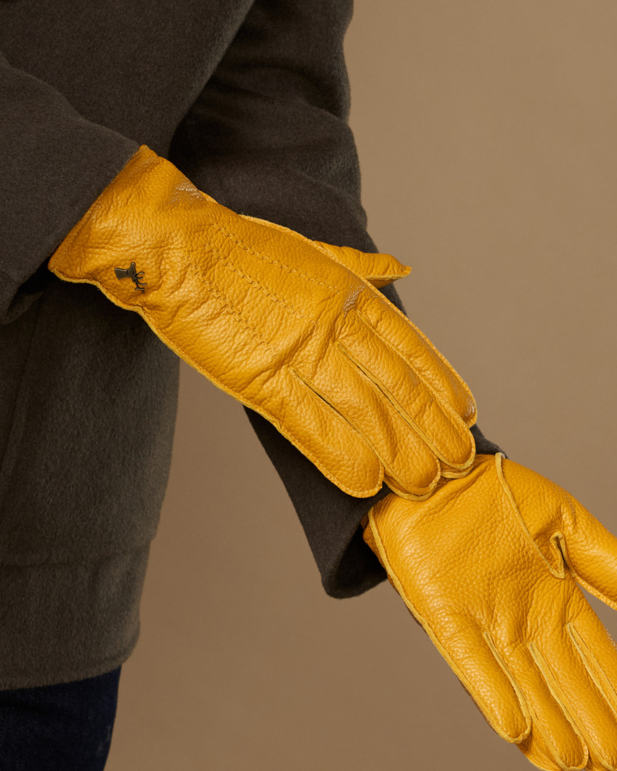 Yellow leather gloves stretched open, long cuffs and finger stitching visible