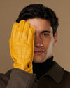Yellow leather glove close-up on model’s hand, fingers and grain texture visible