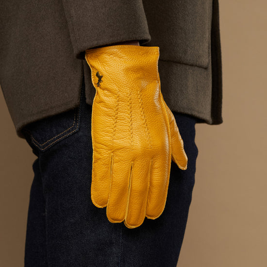 Yellow leather gloves on model, cuffed pair hanging at side