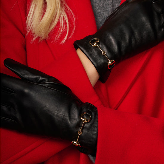 Black leather gloves close-up with gold-tone buckle strap