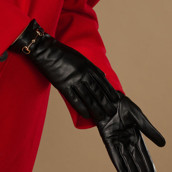 Black leather glove with stitched paneling and gold-tone buckle at cuff