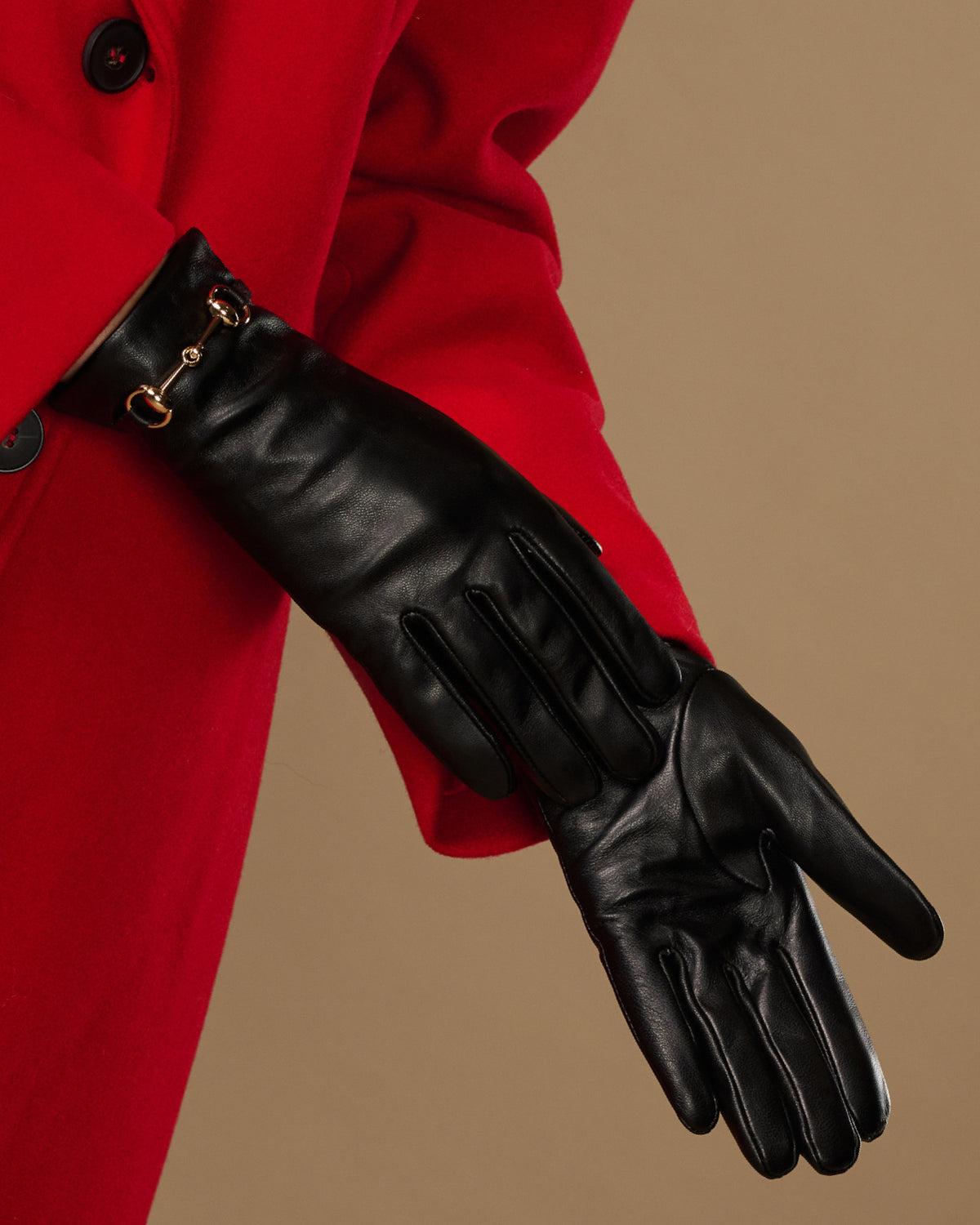 Black leather glove with stitched paneling and gold-tone buckle at cuff
