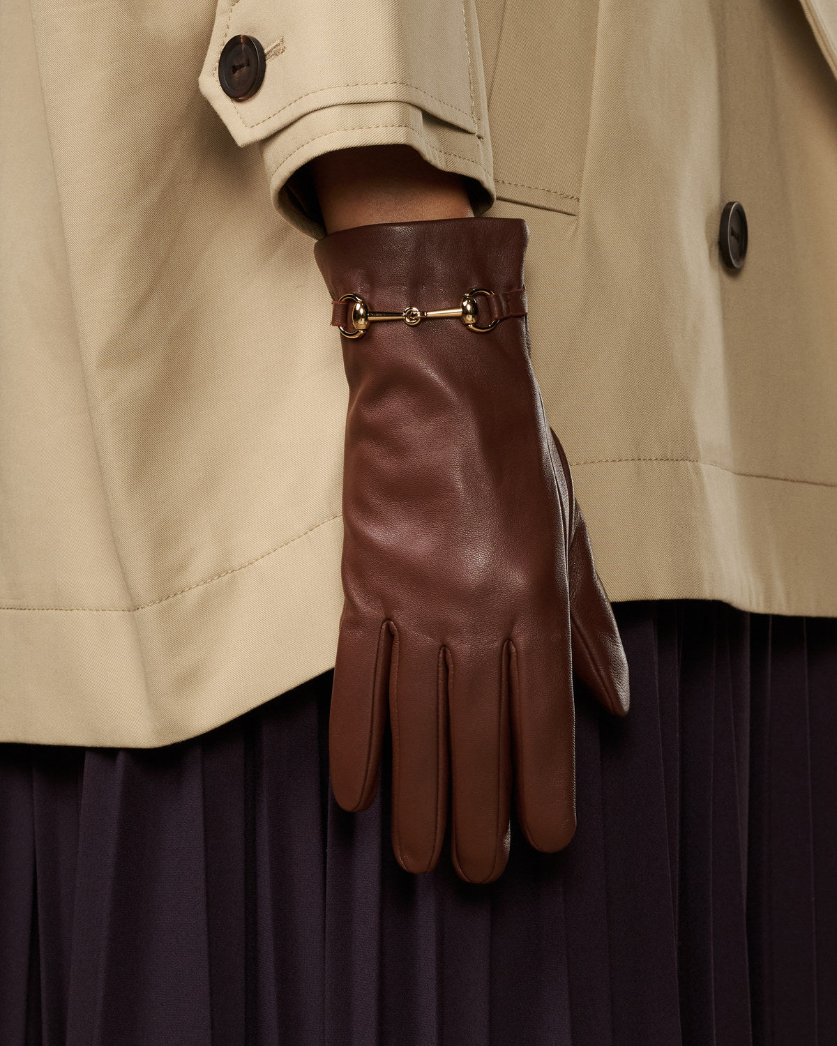 Brown leather gloves with gold-tone buckle strap and separated finger design