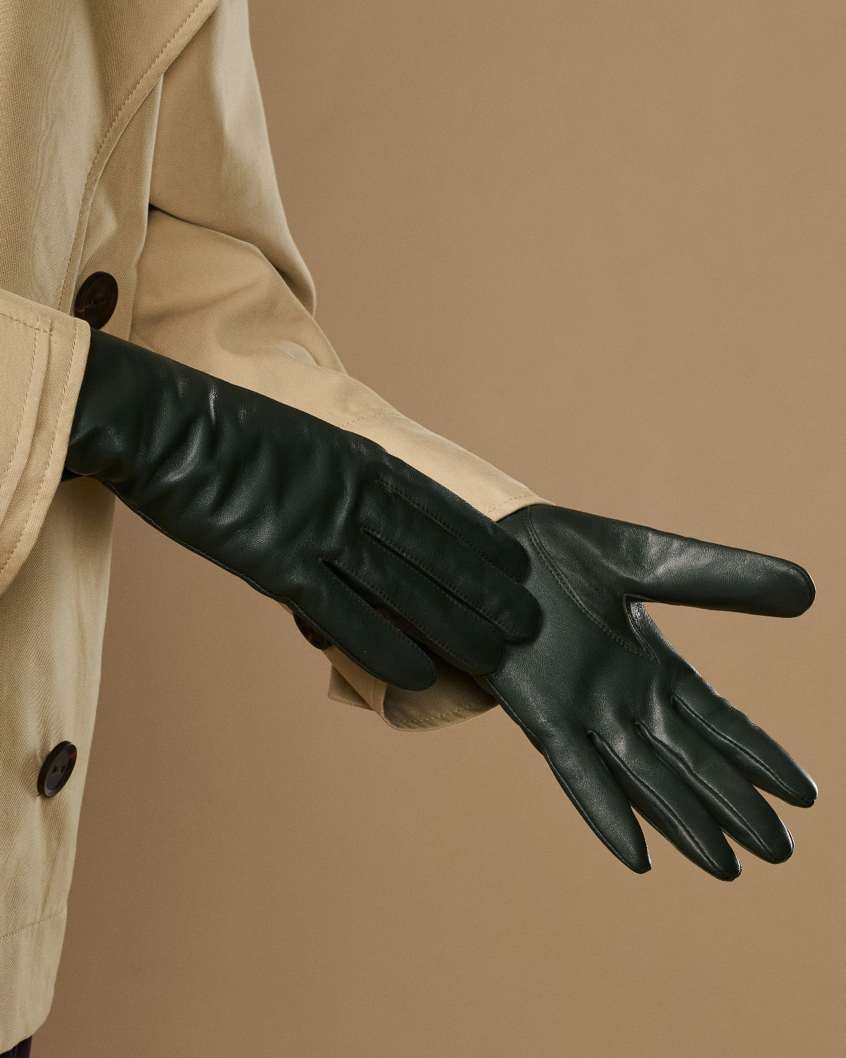 Dark green leather gloves laid out, showing long cuffs and finger seams