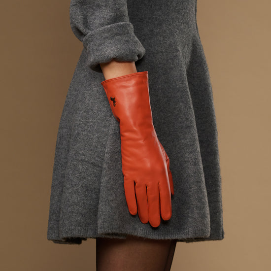 Long orange leather glove with padded wrist and finger seams, cuff extends past sleeve