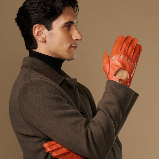 Men's orange lambskin driving gloves with touchscreen, worn palm-out