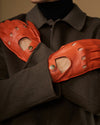 Orange leather driving gloves with stitched knuckles and touchscreen fingertips