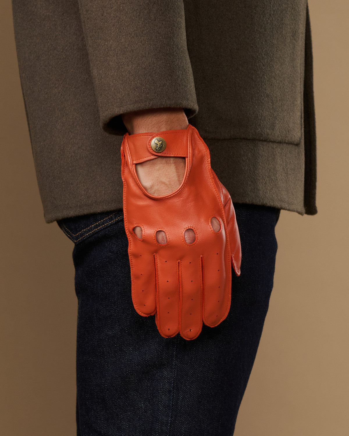 Orange lambskin touchscreen glove, worn at side with thumb opening