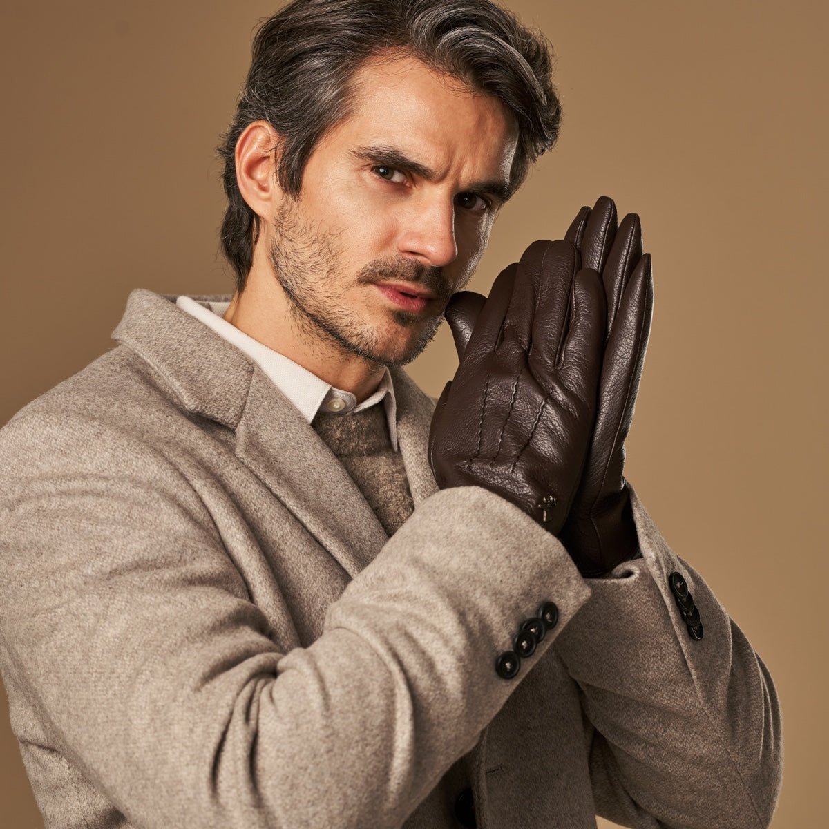Man wearing brown leather gloves with lambswool-lined cuffs and a grey coat