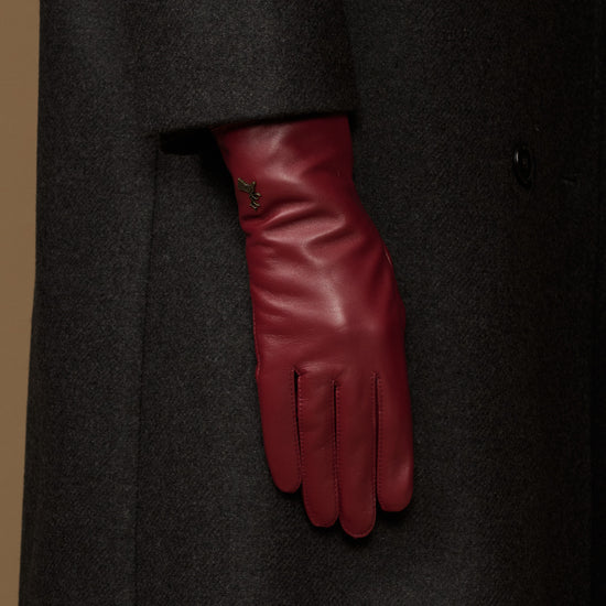 Bordeaux leather glove showing from a dark coat sleeve with stitched cuff