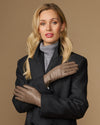 Pair of women’s taupe leather gloves with stitched seams, worn with dark outerwear