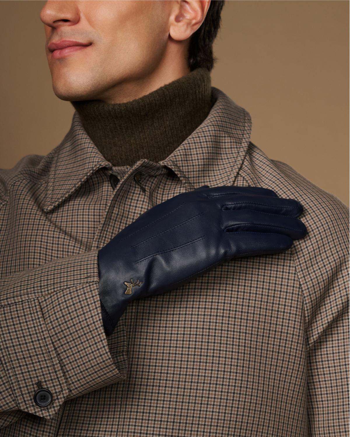 Navy leather glove close-up near the collar, showing stitched knuckles and logo