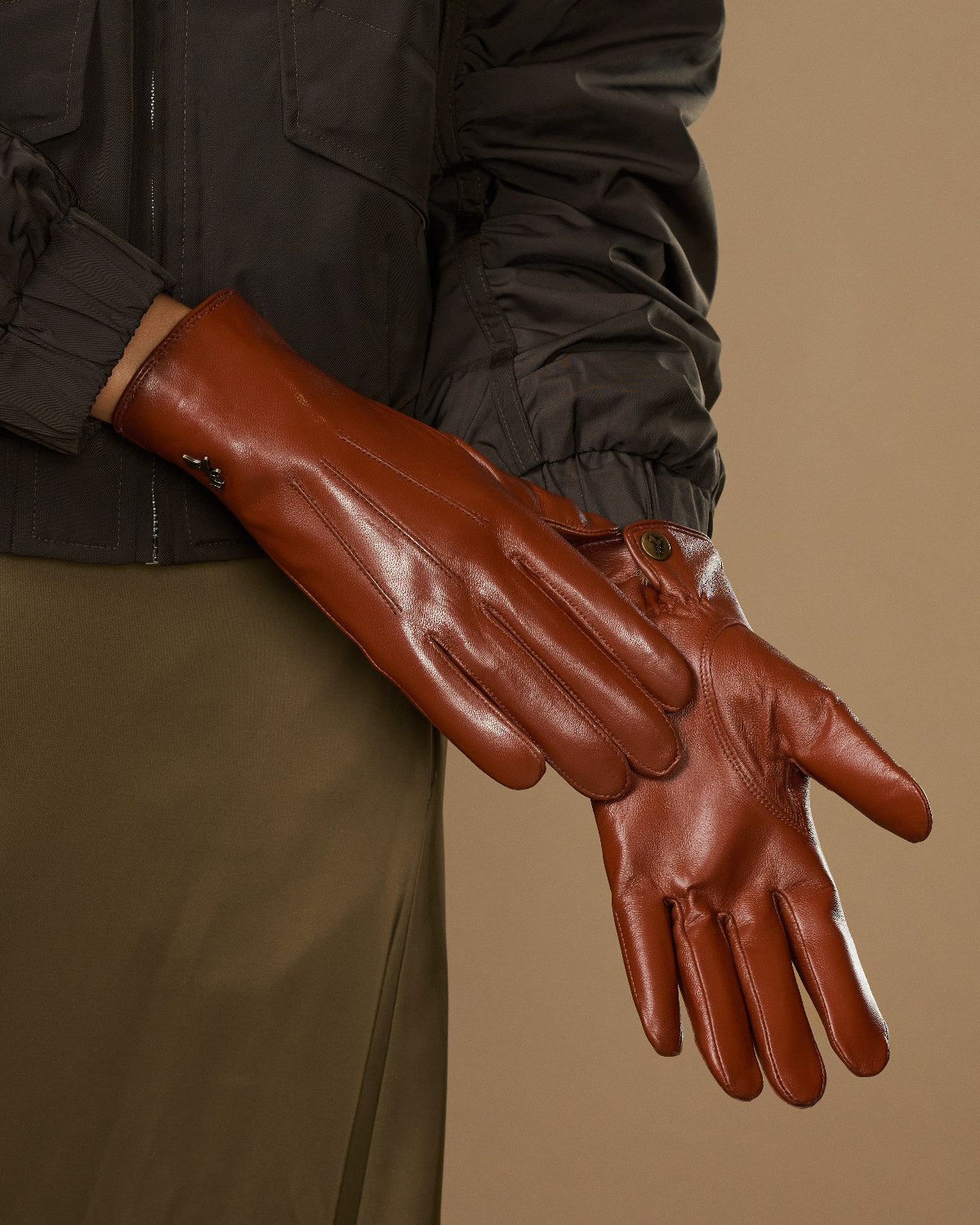 Women’s cognac leather gloves with curved seams and snug wrist band detail