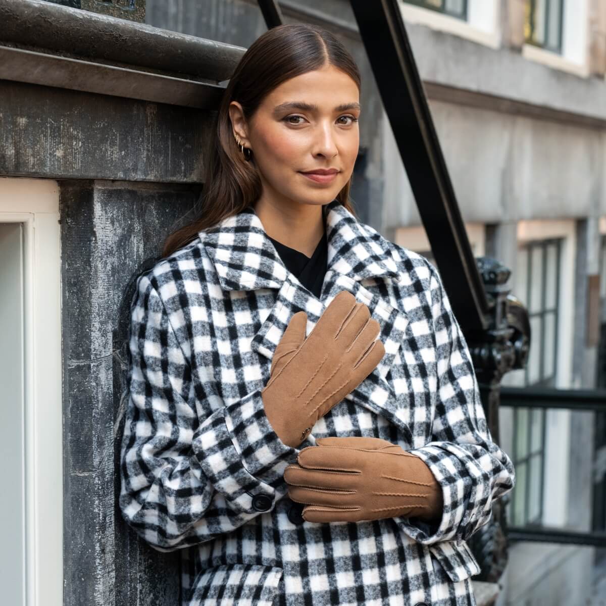 Camel suede leather gloves worn with plaid coat; back-of-hand logo visible.