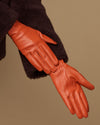 Lauren orange lambskin leather glove close-up, touchscreen tips, silk-lined seam detail