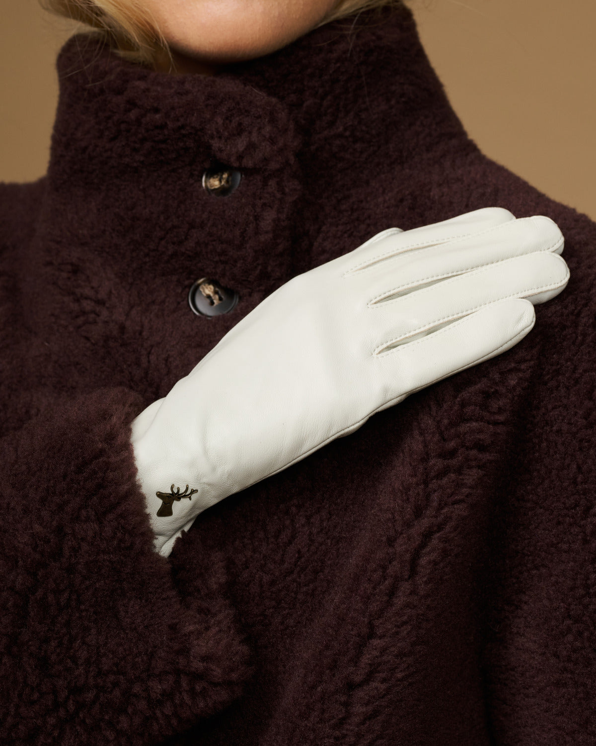Close-up of women’s white leather gloves with stitched finger seams and tapered cuff