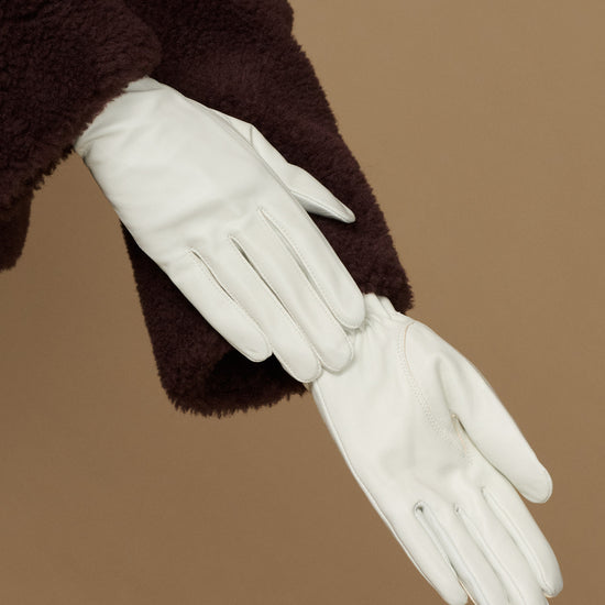 Women’s white leather gloves showing palm and stitched fingertips with slim wrist opening
