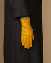Single yellow leather glove with stitched finger seams and structured wrist cuff