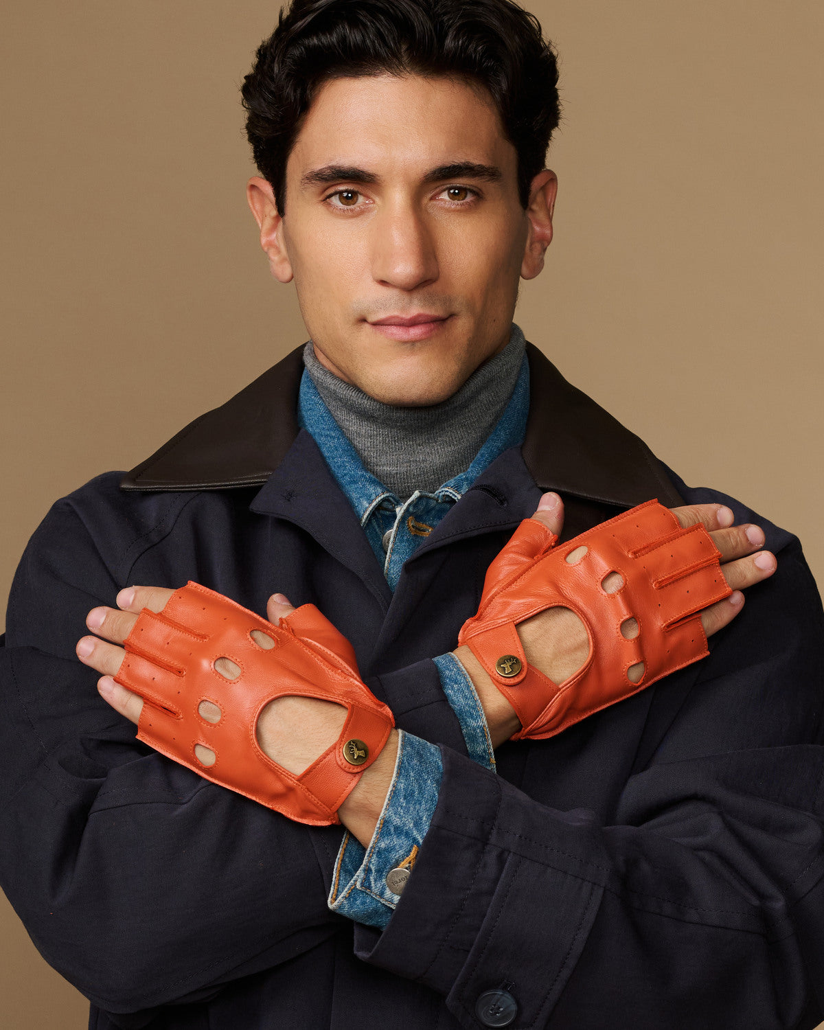 Men's orange fingerless lambskin driving gloves with stitched finger cutouts and cuff tabs