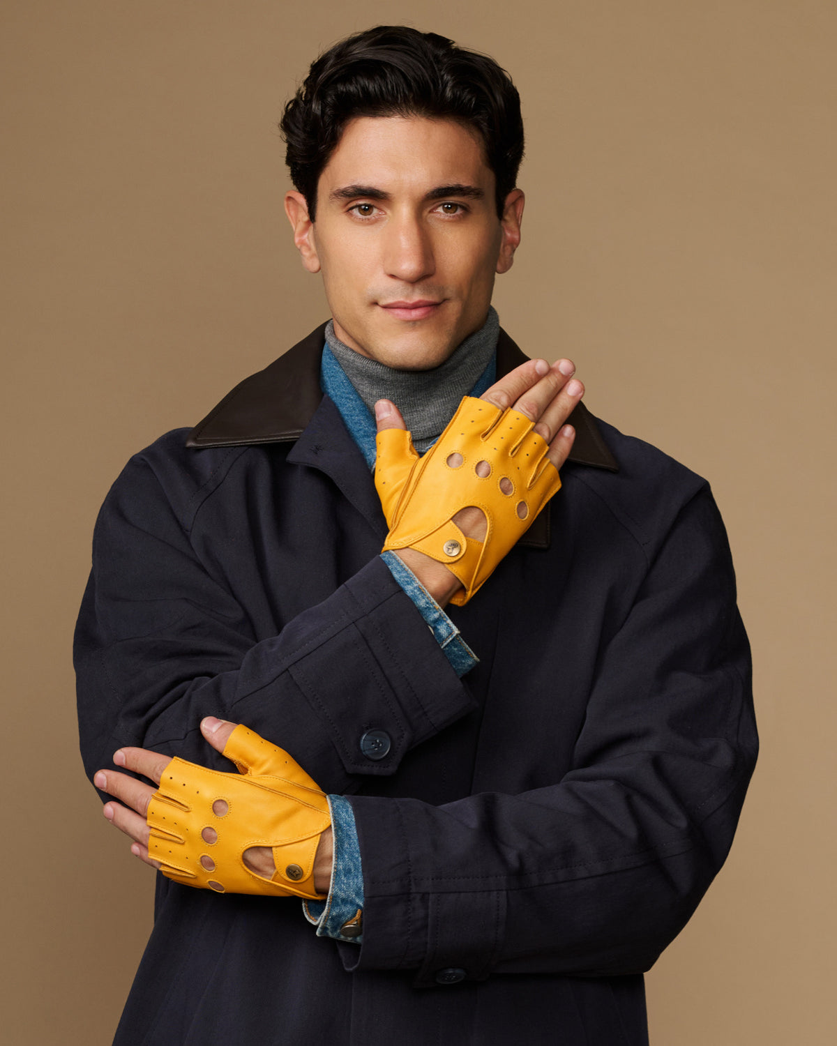 Yellow fingerless driving gloves with perforated panels, palm-forward hand pose