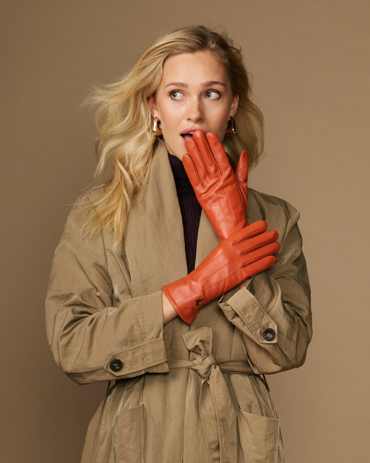 Orange leather gloves with fleece lining, one glove resting against the other