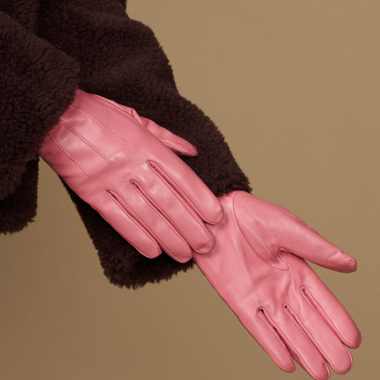 Pink leather glove close-up with stitched fingers and dark cuffs