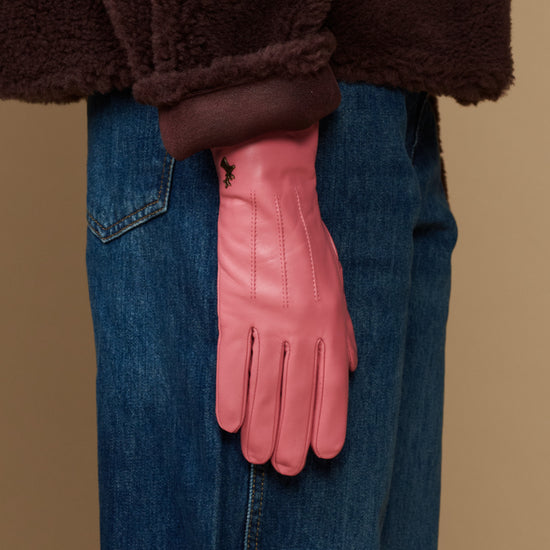 Pink leather glove worn with denim jeans, dark fleece lining at cuff
