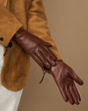 Close-up of brown leather gloves showing stitched seams and side zip