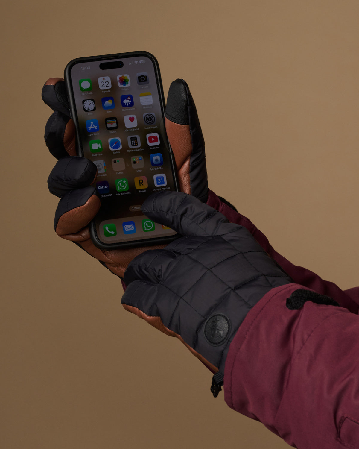 Men's touchscreen gloves holding a smartphone, padded dark gray fabric