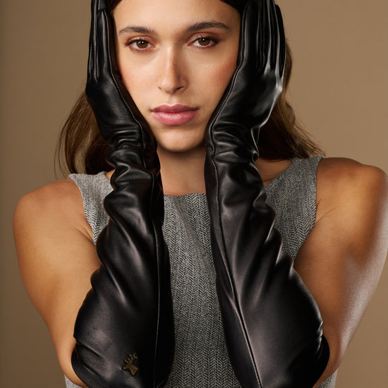 Women’s black lambskin leather elbow gloves with gathered cuff, close-up on model