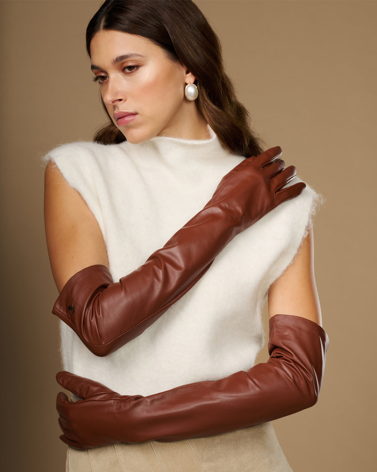 Chestnut brown leather opera gloves in a crossed-arm pose, long sleeves and cuffs