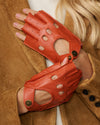 Orange fingerless leather driving gloves, oval cutouts and snap wrist strap