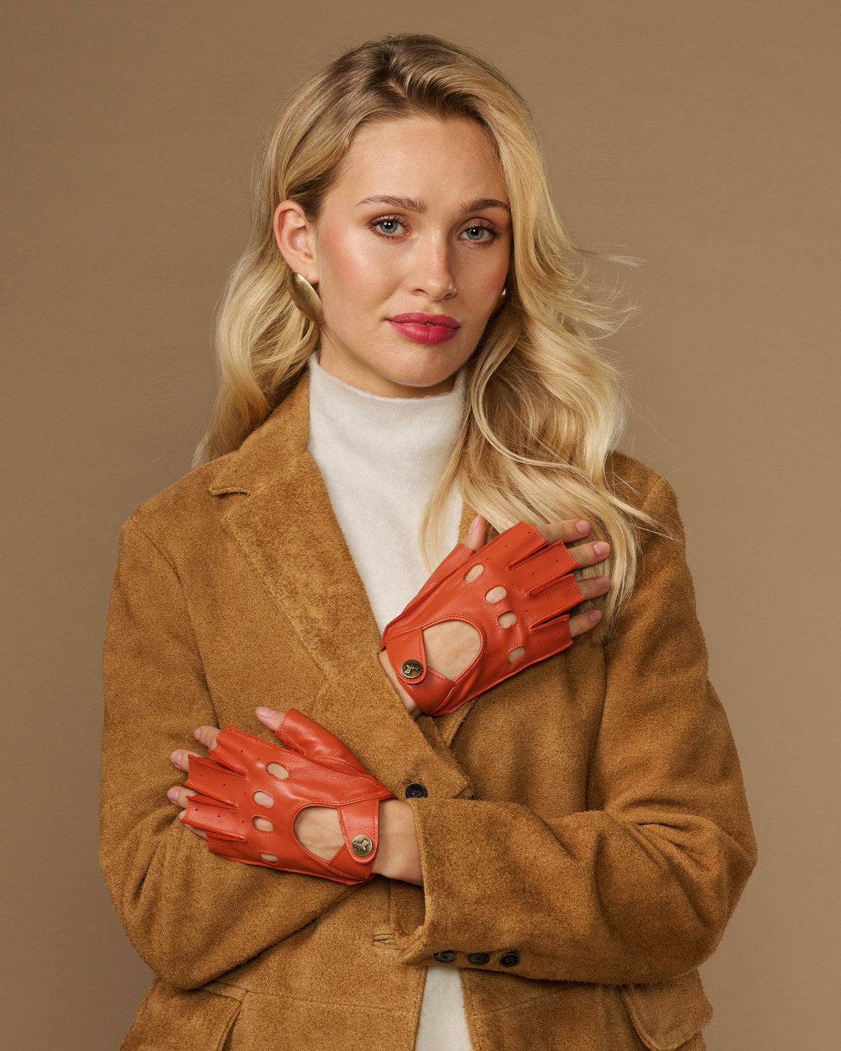 Orange fingerless lambskin driving gloves with open fingers and circular wrist button