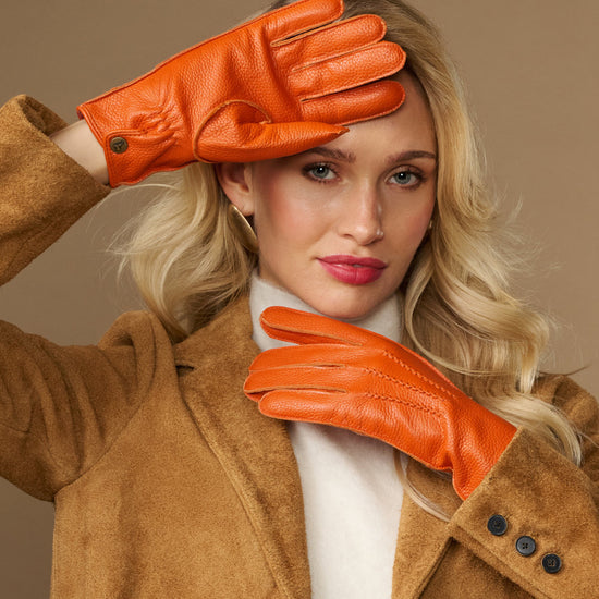 Orange leather deerskin gloves with stitched fingers and soft cuff lining, worn on hands