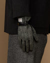 Men's gloves rear view: black leather top and gray herringbone fingers with wrist label.