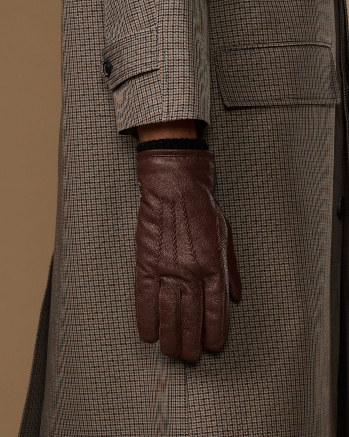 Brown leather glove cuff with black fleece lining and press-stud detail