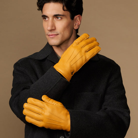 Yellow goatskin leather gloves with stitched details, worn with gray fleece-lined cuffs